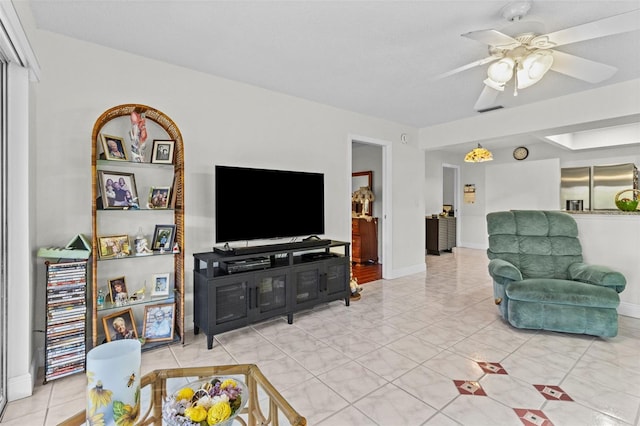 living room featuring tile patterned floors, visible vents, baseboards, and a ceiling fan