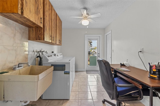 laundry room with a ceiling fan, washing machine and clothes dryer, cabinet space, a sink, and a textured ceiling