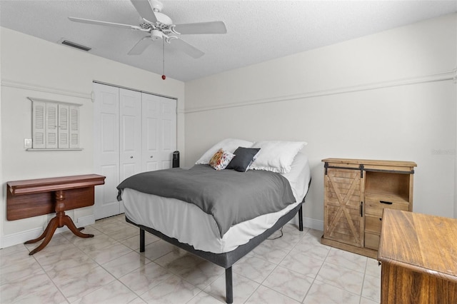 bedroom featuring a ceiling fan, baseboards, visible vents, a closet, and a textured ceiling