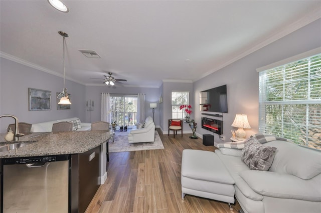 interior space with wood finished floors, visible vents, a sink, stainless steel dishwasher, and open floor plan