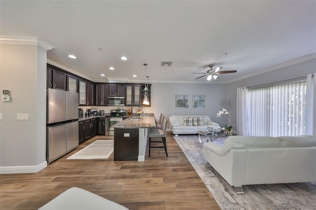 living area with recessed lighting, visible vents, wood finished floors, and crown molding