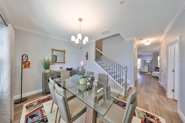 dining room featuring light wood-type flooring, stairway, a notable chandelier, and ornamental molding