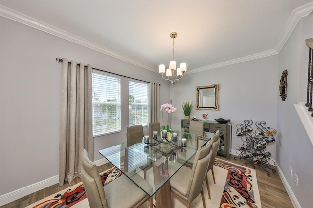 dining room featuring a chandelier, crown molding, baseboards, and wood finished floors