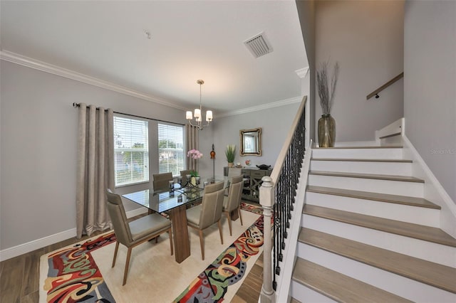 dining space featuring visible vents, stairs, ornamental molding, an inviting chandelier, and wood finished floors