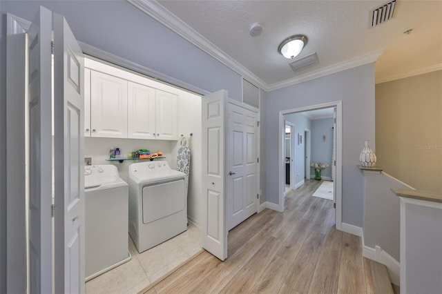 laundry area featuring visible vents, washing machine and dryer, cabinet space, light wood-style floors, and crown molding