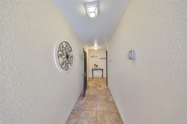 hall with stone tile flooring and a textured wall