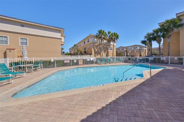 community pool with a patio area and fence