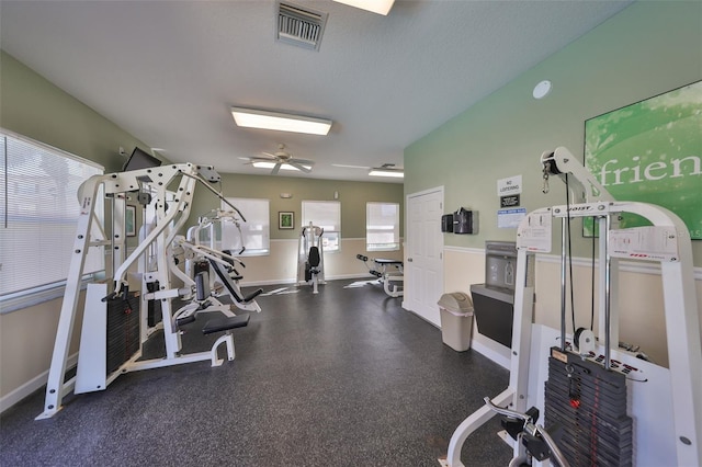 exercise room featuring ceiling fan, baseboards, visible vents, and a textured ceiling