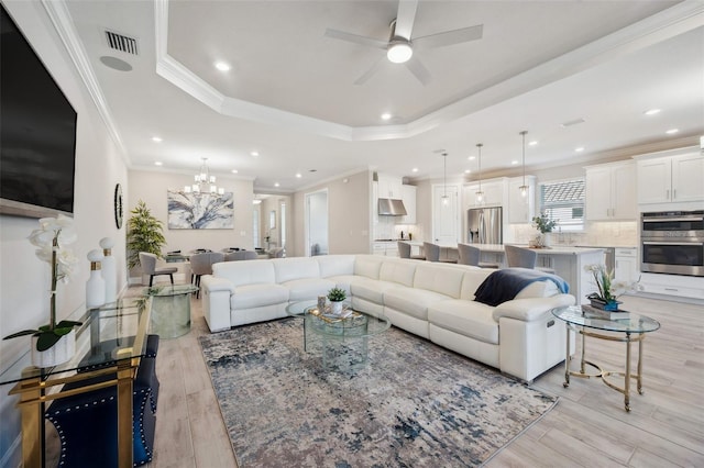 living area featuring visible vents, ceiling fan with notable chandelier, recessed lighting, light wood finished floors, and a raised ceiling