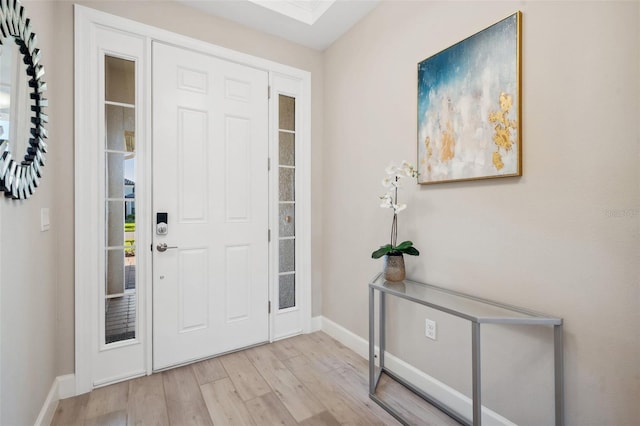 foyer entrance featuring light wood-type flooring, baseboards, and a skylight