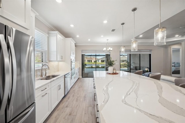 kitchen featuring a sink, stainless steel appliances, crown molding, and white cabinetry