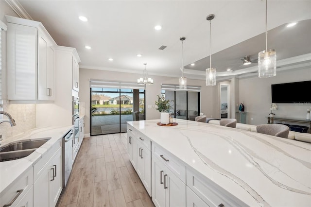 kitchen featuring crown molding, open floor plan, decorative backsplash, white cabinetry, and a sink