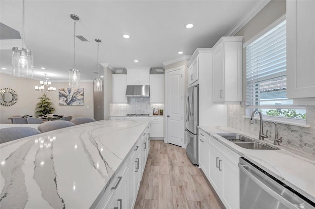 kitchen featuring under cabinet range hood, crown molding, appliances with stainless steel finishes, and a sink