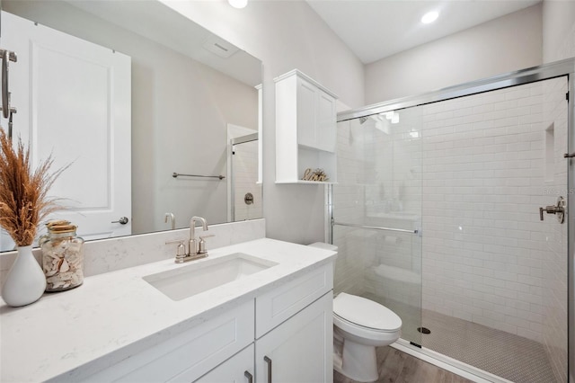 full bathroom featuring a shower stall, toilet, vanity, and wood finished floors