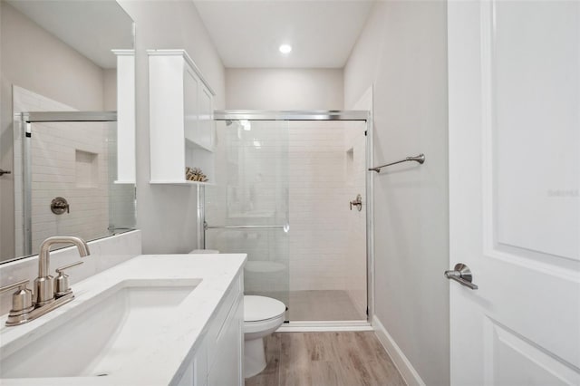 bathroom with toilet, wood finished floors, a stall shower, and baseboards