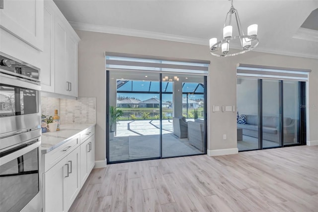 unfurnished dining area with light wood-type flooring, a notable chandelier, and crown molding