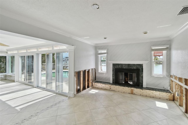 unfurnished living room with tile patterned flooring, visible vents, ornamental molding, a fireplace, and a textured ceiling