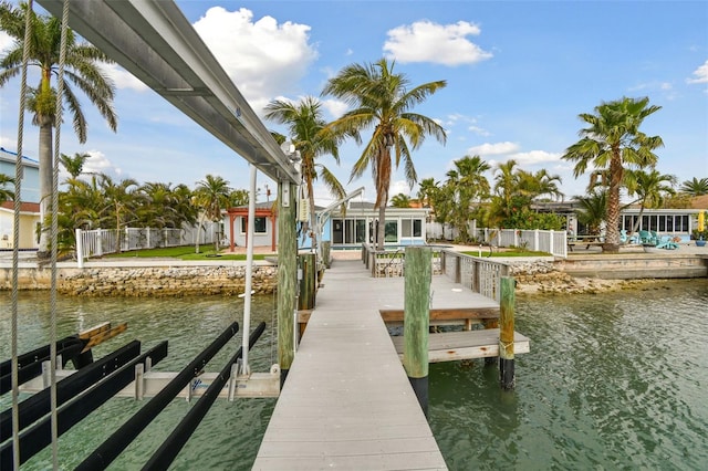 view of dock with boat lift, fence, and a water view