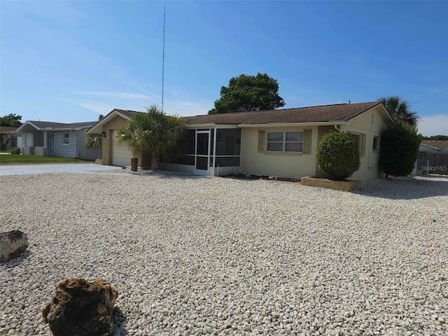 ranch-style house featuring stucco siding, driveway, a garage, and a sunroom