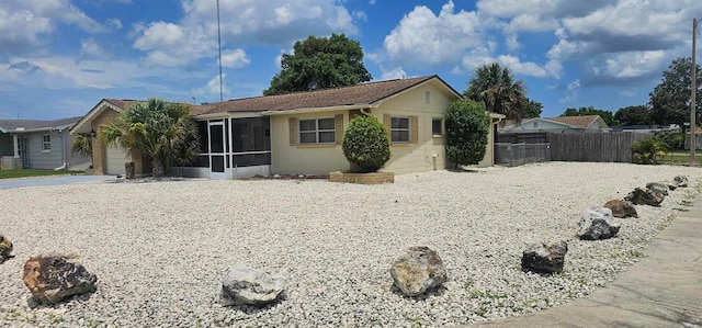 single story home featuring fence, driveway, a sunroom, stucco siding, and a garage