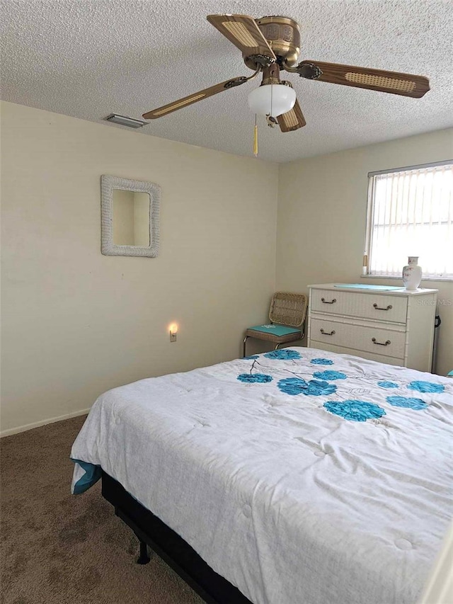 bedroom featuring ceiling fan, visible vents, carpet floors, and a textured ceiling