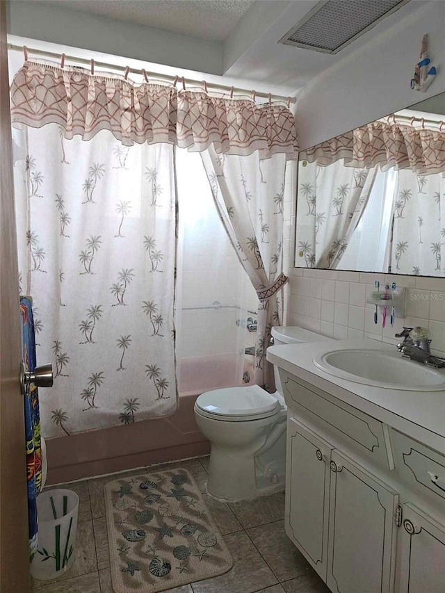 bathroom with tile patterned floors, shower / bath combo with shower curtain, toilet, a textured ceiling, and vanity