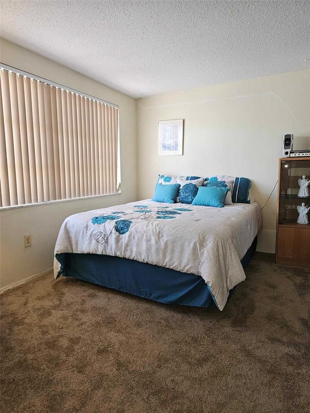 bedroom featuring carpet, baseboards, and a textured ceiling