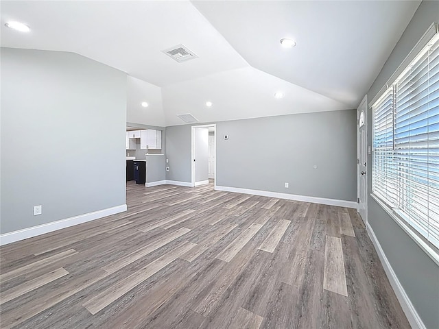 unfurnished living room with visible vents, baseboards, dark wood-style flooring, and vaulted ceiling