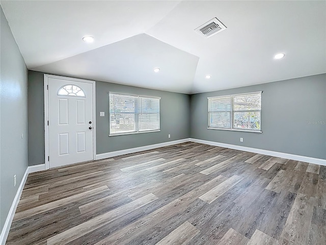 foyer entrance featuring visible vents, wood finished floors, baseboards, and vaulted ceiling