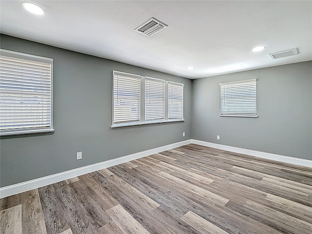 empty room featuring visible vents, baseboards, and wood finished floors