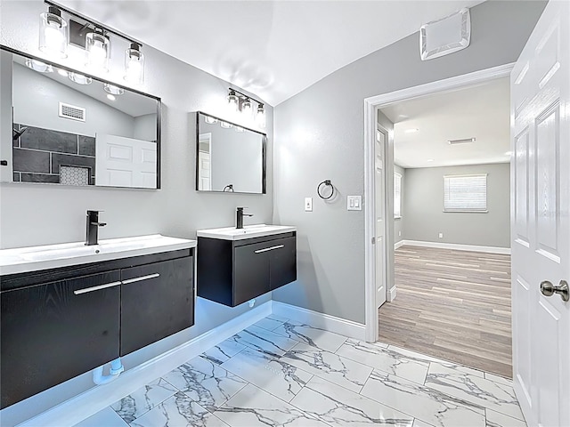 full bath with a sink, baseboards, two vanities, and marble finish floor