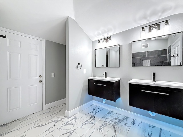 bathroom featuring two vanities, marble finish floor, a sink, a tile shower, and baseboards