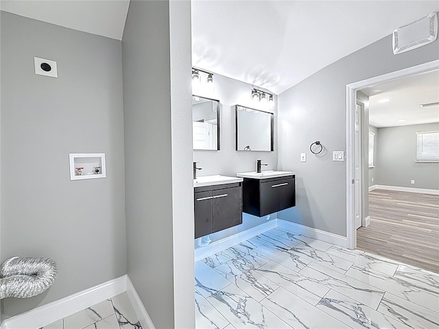 bathroom featuring a sink, baseboards, two vanities, and marble finish floor