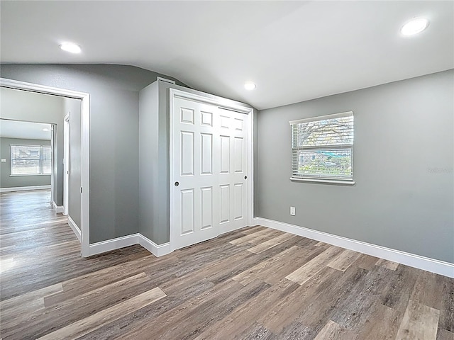 unfurnished bedroom with baseboards, lofted ceiling, a closet, and wood finished floors