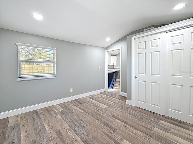 unfurnished room featuring visible vents, baseboards, lofted ceiling, and wood finished floors