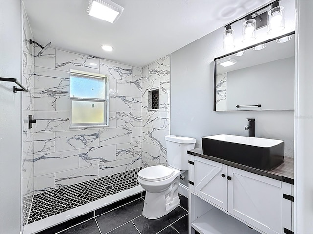 bathroom with vanity, toilet, tile patterned flooring, and tiled shower