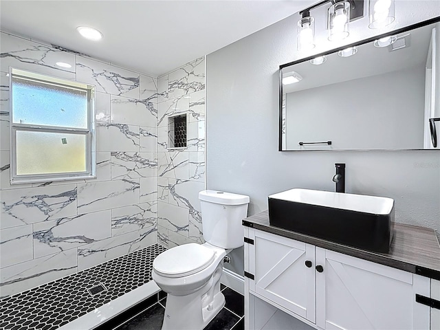 full bathroom featuring visible vents, baseboards, toilet, a tile shower, and vanity