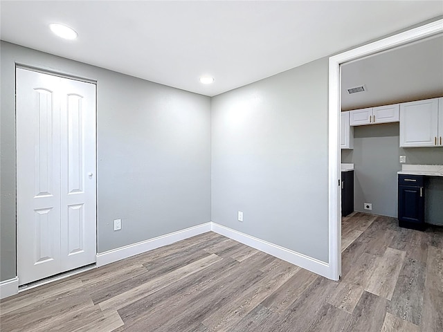 unfurnished room with light wood-type flooring, visible vents, and baseboards