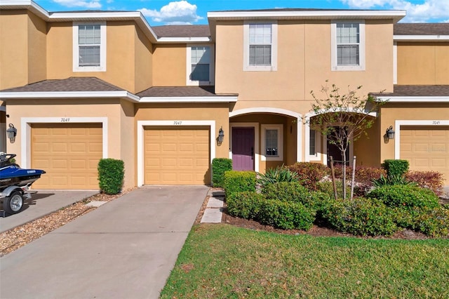 view of property featuring stucco siding, an attached garage, and driveway