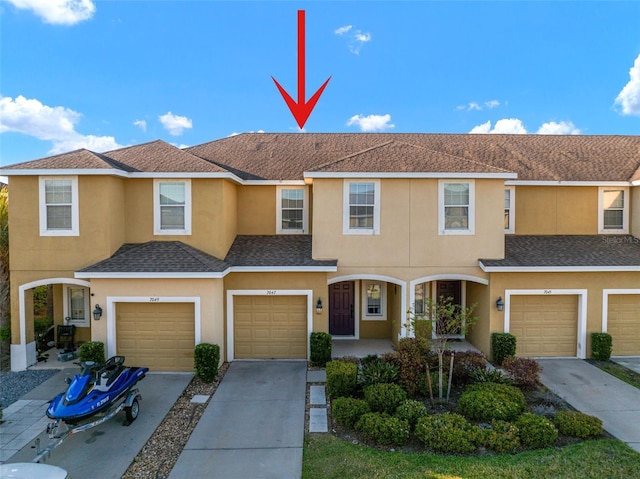 townhome / multi-family property with stucco siding, concrete driveway, a garage, and a shingled roof