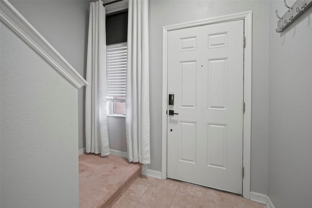 entryway featuring light tile patterned floors, baseboards, and light carpet