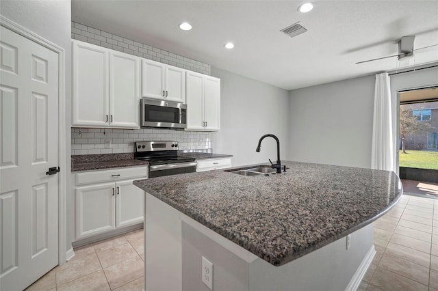 kitchen with visible vents, a sink, stainless steel appliances, white cabinets, and backsplash