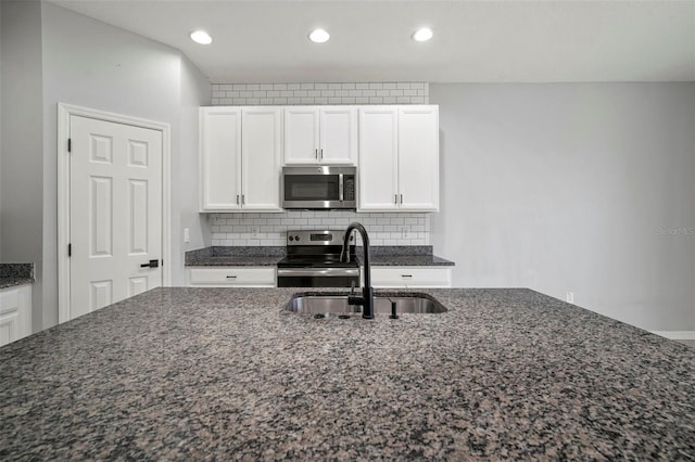 kitchen featuring a sink, stainless steel appliances, backsplash, and white cabinets