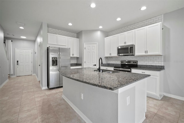 kitchen with an island with sink, a sink, backsplash, white cabinetry, and stainless steel appliances