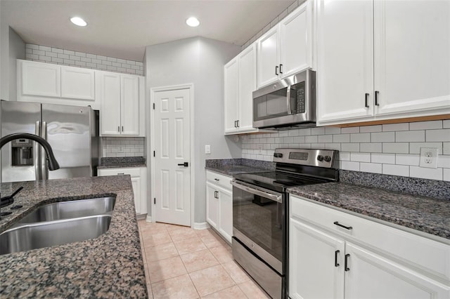 kitchen featuring white cabinetry, dark stone counters, appliances with stainless steel finishes, and a sink