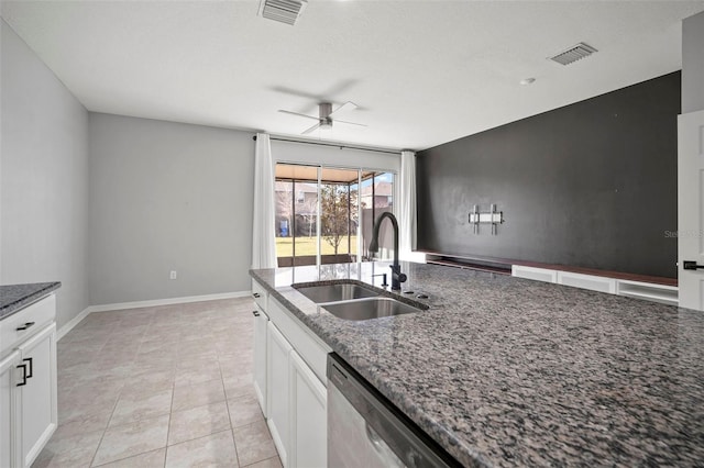 kitchen with a sink, visible vents, a ceiling fan, and dark stone countertops