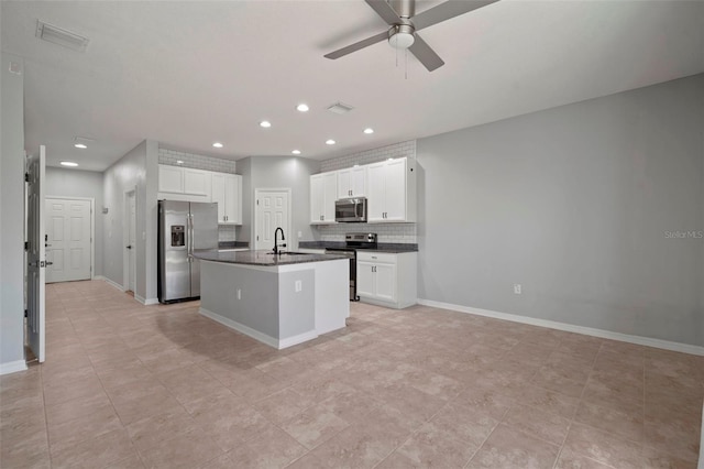 kitchen featuring dark countertops, visible vents, stainless steel appliances, a ceiling fan, and a sink