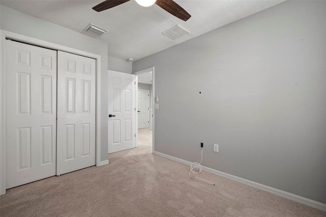 unfurnished bedroom with visible vents, light colored carpet, and a closet