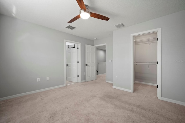 unfurnished bedroom featuring visible vents, baseboards, a walk in closet, and carpet flooring