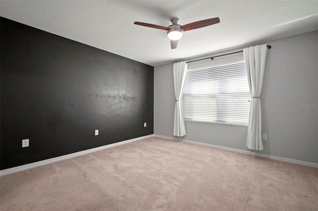 carpeted spare room with baseboards, a textured ceiling, and a ceiling fan